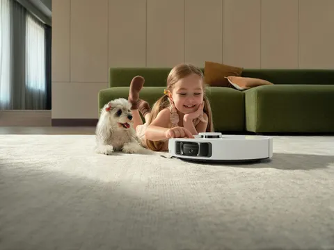 Een meisje en een hond kijken naar een robotstofzuiger
