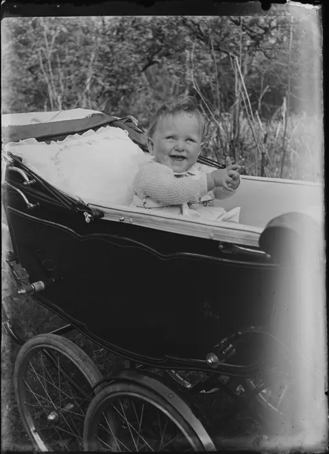 Baby in een zwarte kinderwagen in vintagestijl